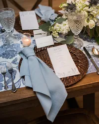 Escort cards and blue linen napkins on a table