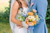 Close up of the bride's bouquet beside the groom's blue suit