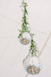 Hanging disco balls wrapped in trailing greenery