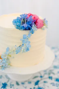 White wedding cake topped with blue and pink flowers