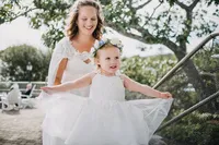 Flower girl in a white dress with a floral crown twirling on the lawn at French's Point