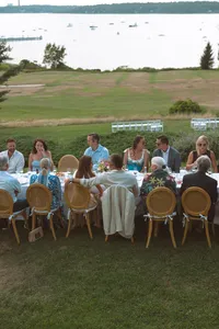 Guests at long tables during dinner on the lawn