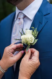 Boutonniere being pinned onto a navy suit