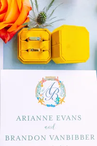 Yellow ring box beside the couple's monogrammed stationery