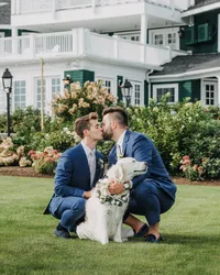Grooms posing with a golden retriever on the lawn