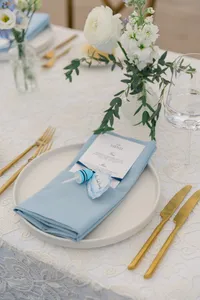 Place setting with a blue napkin, gold flatware and a menu