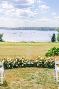 Ceremony site on the lawn lined with florals above the water