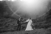 Brautpaar beim Brautpaarshooting in der Region Zurzach im Kanton Aargau, Hand in Hand in einer weiten Natur- und Berglandschaft, schwarzweisse Hochzeitsfotografie mit natürlichem, emotionalem Storytelling einer Hochzeitsfotografin aus der Schweiz.