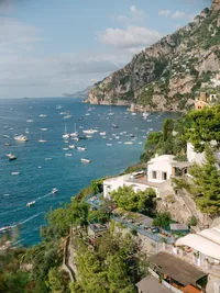 Cliffside view of the Amalfi Coast with boats scattered on the turquoise water, perfect for luxury destination weddings in Positano.