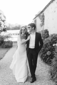 Couple de mariés élégant marchant ensemble à Nantes, portrait spontané en noir et blanc avec lunettes de soleil.