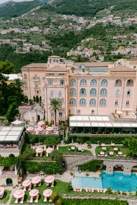 Aerial view of Palazzo Avino in Ravello, a luxury wedding venue on the Amalfi Coast with gardens, pool, and pink umbrellas.