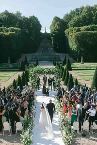 Bride walking down the aisle under a floral arch in a French garden ceremony, documented by Paris wedding photographer Thomas Raboteur