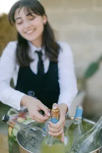 Waitress opening Italian sparkling wine during wedding reception – detail of authentic Italy wedding experience.