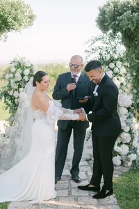 Luxury outdoor wedding ceremony in Italy – bride and groom exchanging vows under floral arch with Mediterranean views.
