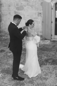 Groom adjusting bride’s dress before wedding ceremony – emotional candid moment captured in Italy.