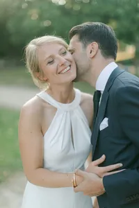 Marié embrassant sa femme sur la joue lors d’un mariage en extérieur à Nantes, instant joyeux et romantique.
