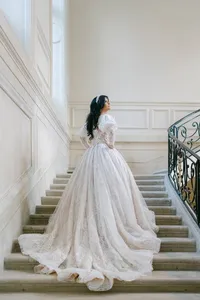 Bride in a regal lace wedding gown ascending an elegant stone staircase, photographed by Paris wedding photographer Thomas Raboteur