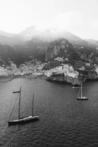 Black and white photograph of Amalfi town and coastline with sailing yachts — timeless scenery for destination weddings in Italy.