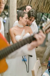 Bride and groom celebrating surrounded by guests under string lights – candid Italy wedding reception photography.