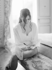 Bride writing her vows in natural window light, a timeless black and white moment by Paris wedding photographer Thomas Raboteur