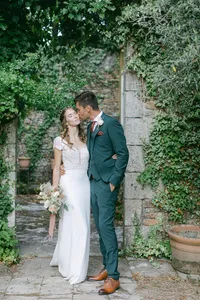 Couple de mariés dans un jardin romantique près de Nantes, entourés de murs recouverts de lierre.