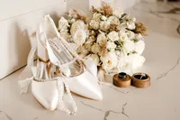 a close up detail shot of the brides shoes, rings, and flowers in the bridal suite.
