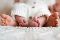 a close of up photo of big sisters feet with baby brothers feet in between captured by shelly voss.