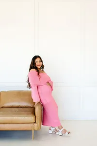 a modern mom leans against a sofa during her studio maternity session in plano,texas.