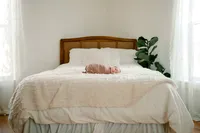 a baby lays swaddled laying on the bed while shelly voss captures the moment.
