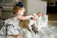 a new big sister touches her baby brothers toes during their newborn session with shelly voss.