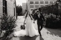 a bride and groom walk hand in hand in an ally at their abilene texas wedding