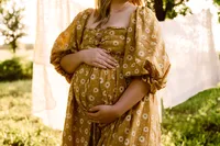 a mom cradles her belly in a daisy custom gown during her maternity session with shelly voss.