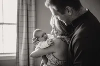 a new mom and dad smile at their new baby boy during their newborn session with shelly voss.