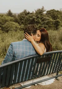 bride and groom sitting on bench kissing