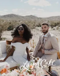 Kohnur modern boho bride in an off-shoulder jumpsuit with natural makeup and voluminous hair with groom in desert landscape featured on 100 Layer Cake.
