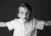 Black and white school portrait of young boy in glasses showing his personality.