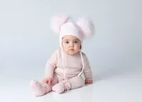 little-girl-in-light-pink-hat-with-fluffy-pom-poms