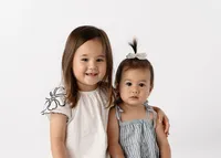 Young sisters with arms around each other for their school portrait.