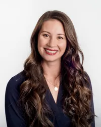 Headshot-of-woman-with-long-curly-hair-and-navy-shirt