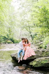Abby and Joseph’s engagement session at Looking Glass Falls near Asheville, North Carolina, captures them sitting on a river rock in golden sunlight—like a scene from Huckleberry Finn—photographed by North Carolina wedding photographer Jessica Leigh Mason.