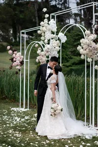 A groom kissing his bride beneath their ceremony arches