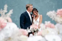 Bride and groom standing close together against a blue wall