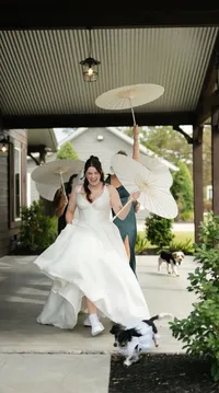 Woman holding paper umbrella walking out of her wedding in a luxury wedding gown.