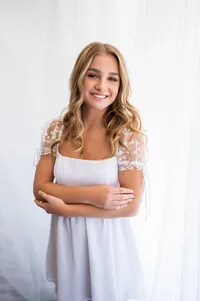 A student from Arrowhead High School poses for her senior pictures in our Downtown Waukesha photo studio wearing all white.