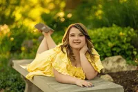 A girl from Waukesha West High School lays on a concrete bench at Lapham Peak for her senior portraits.