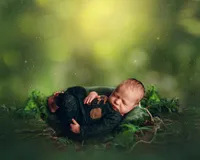 Woodland-themed newborn session featuring a baby boy in a green outfit with mossy forest props, captured by a Pewaukee baby photographer.