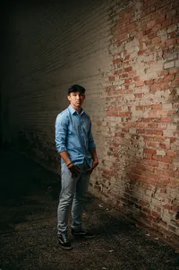 A young man from Waukesha West High School stands along a distressed brick wall in the Downtown area for his senior portraits.