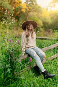 A girl from Kettle Moraine High School perches on a split rail fence in Eagle's Paradise Springs while having her senior photos taken.