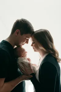 Studio-lit image of parents holding their newborn with foreheads touching, captured by a trusted newborn photographer in Waukesha County.