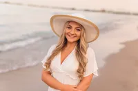 High school senior girl wearing a white dress and hat on the shores of Lake Michigan.